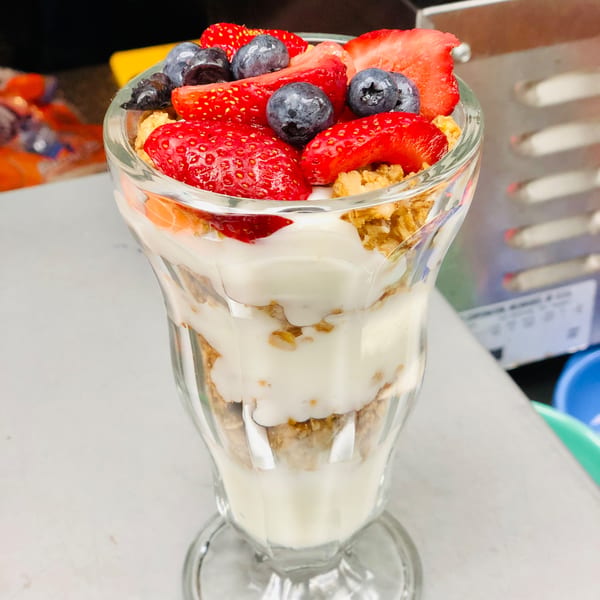 A parfait glass filled with layers of yogurt, granola, strawberries, and blueberries.